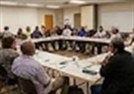 Residents seated around tables at a community meeting