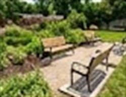 A landscaped neighborhood park with benches along a paved path